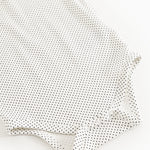 Baby bodystocking with small black dots, long sleeves and buttons at the legs.