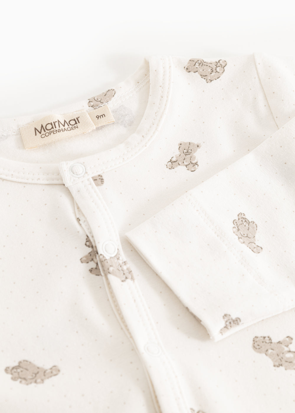 Off‑white blouse with teddy bear print, snap button closure at the neckline.