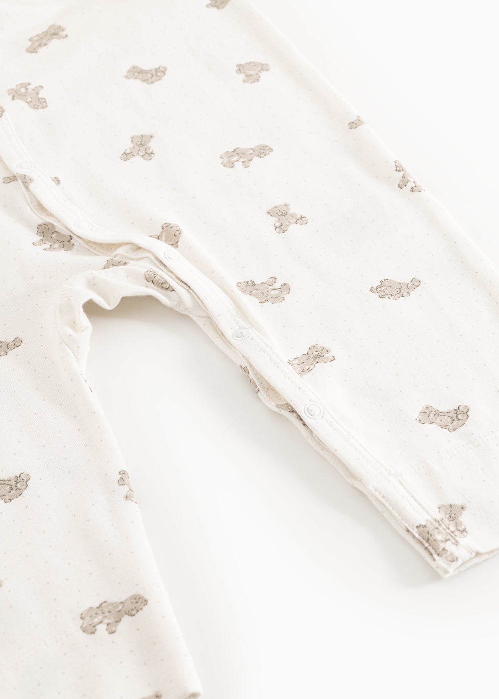 Off-white jumpsuit with teddy bear print, leg openings with snap buttons