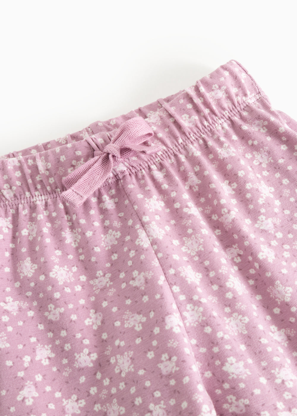 Pink baby pants with elastic waistband and front knot, pattern of small flowers.