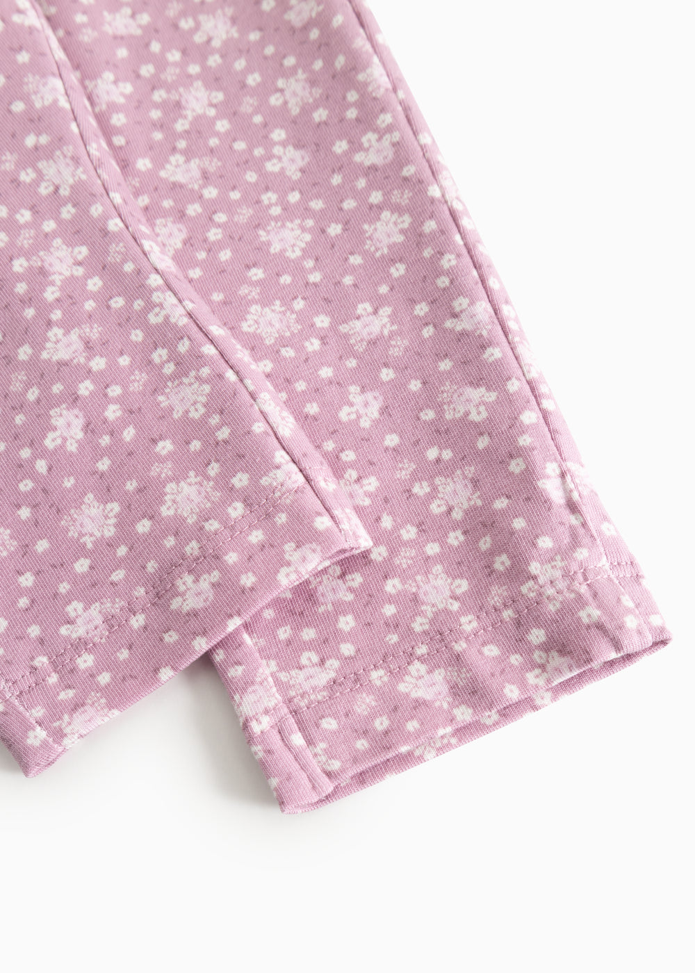 Pink pants legs with small flowers in a tight pattern and a straight seam at the knee.