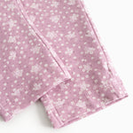 Pink pants legs with small flowers in a tight pattern and a straight seam at the knee.