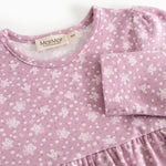 Details of a pink dress with floral print, round neckline, and pleated bust.