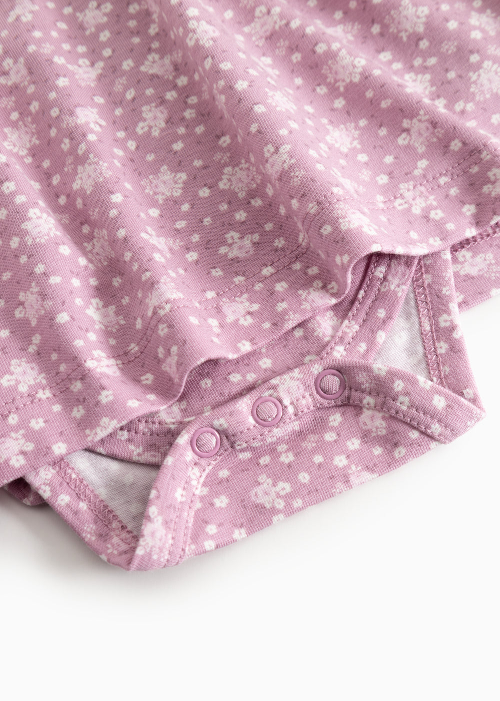 Pink dress with floral print and printed stitching at the bottom, close-up.