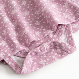 Pink dress with floral print and printed stitching at the bottom, close-up.