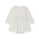 White dress with small black dots, long sleeves and a pleated wide skirt.