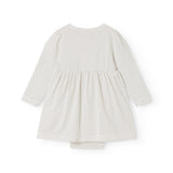 White dress with small black dots, long sleeves and a pleated wide skirt.