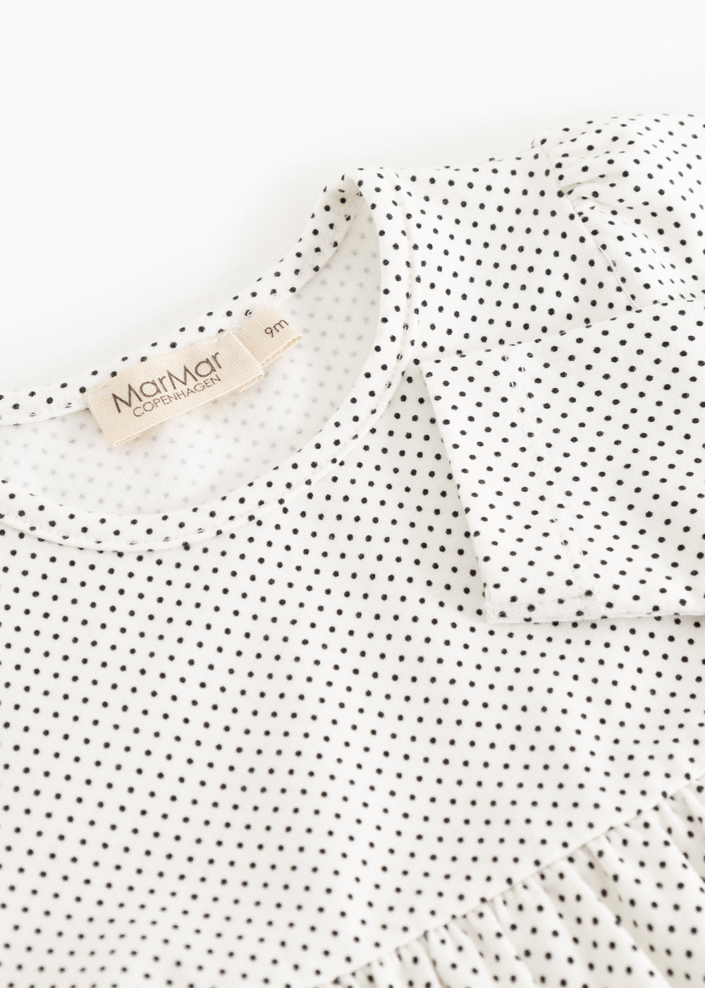 The dress's neckline and label, white with small black dots.