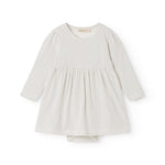 White dress with small black dots, long sleeves and a pleated skirt.