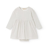 White dress with small black dots, long sleeves and a pleated skirt.