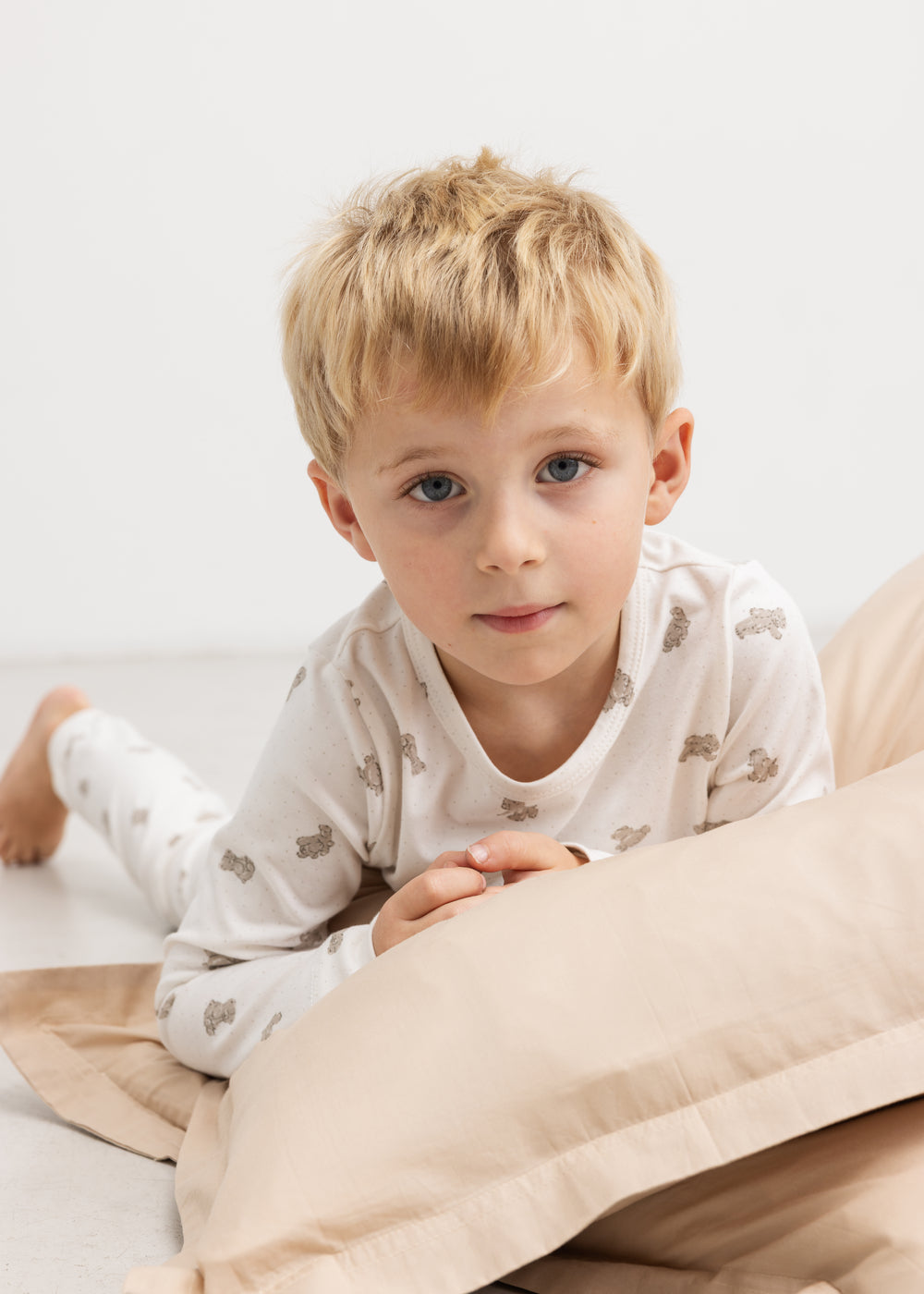 Kids pajamas in off‑white with teddy bear print, shown on children.