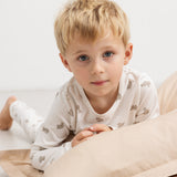Kids pajamas in off‑white with teddy bear print, shown on children.