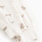 White teddy bear sweatshirt with teddy bear print at the cuff and hem.