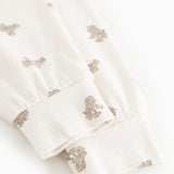 White teddy bear sweatshirt with teddy bear print at the cuff and hem.