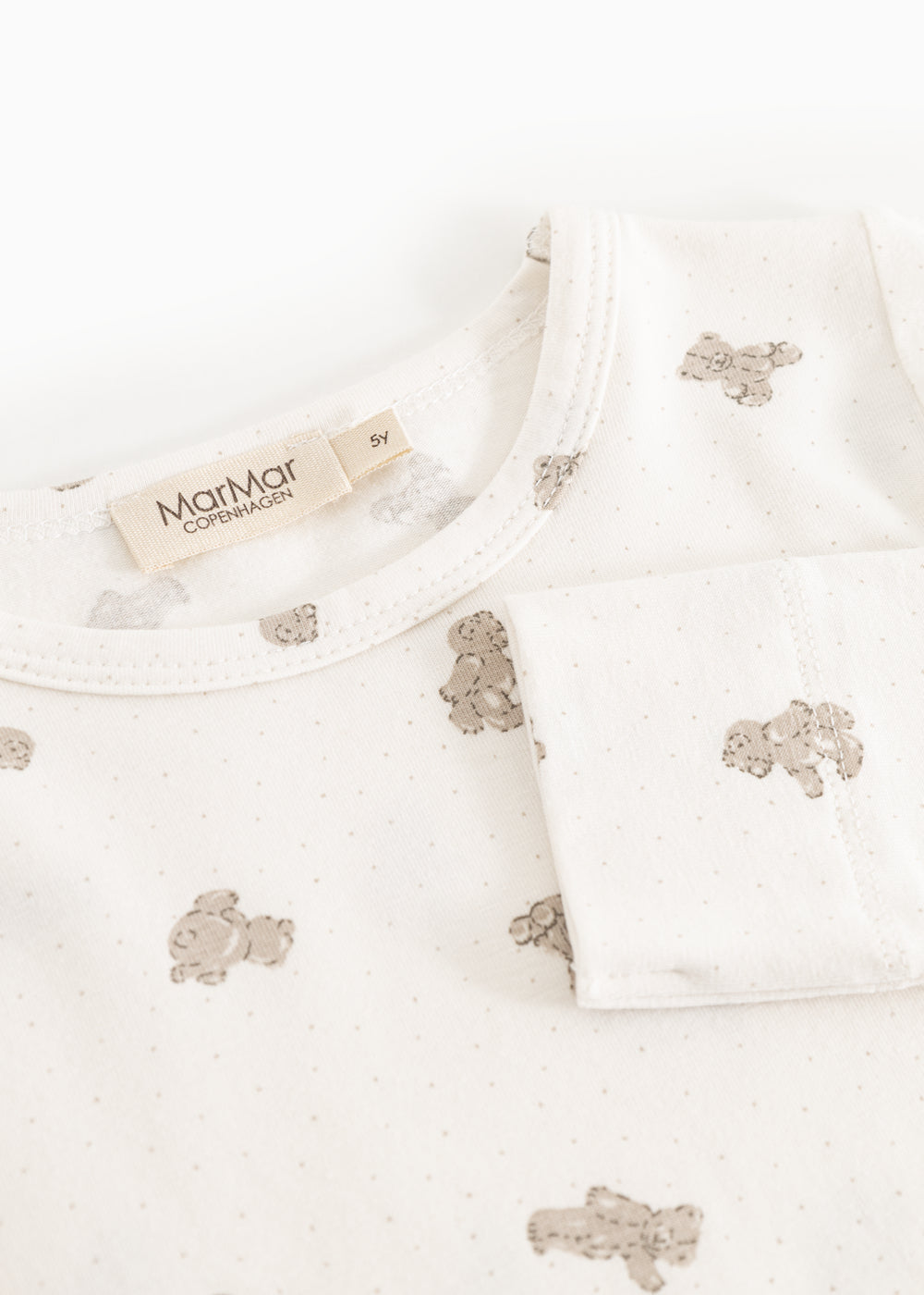 Offwhite pajamas top with round neck, teddy bear print and label.