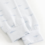 Kids sleepwear close-up: blue whales on white fabric and elastic edge at the leg hem.