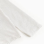 Long-sleeve white T-shirt with small black dots, close-up of sleeve and seam.