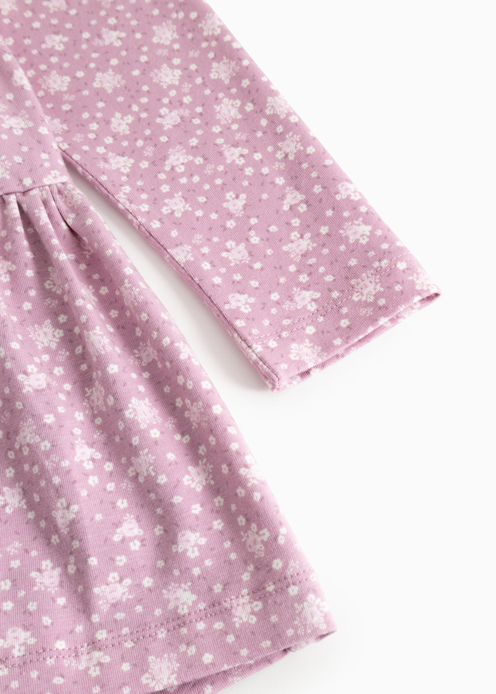 Lilac/pink dress with small white flowers, long sleeves and a pleated skirt.