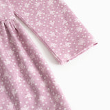 Lilac/pink dress with small white flowers, long sleeves and a pleated skirt.