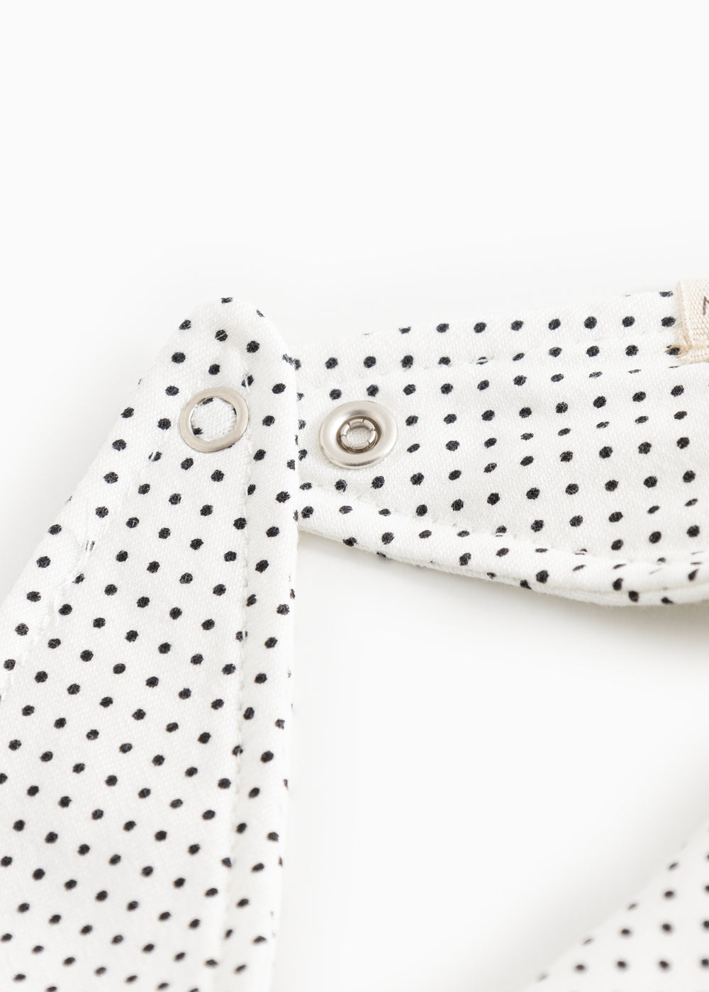 White triangular plush toy with small black dots and metal snap buttons