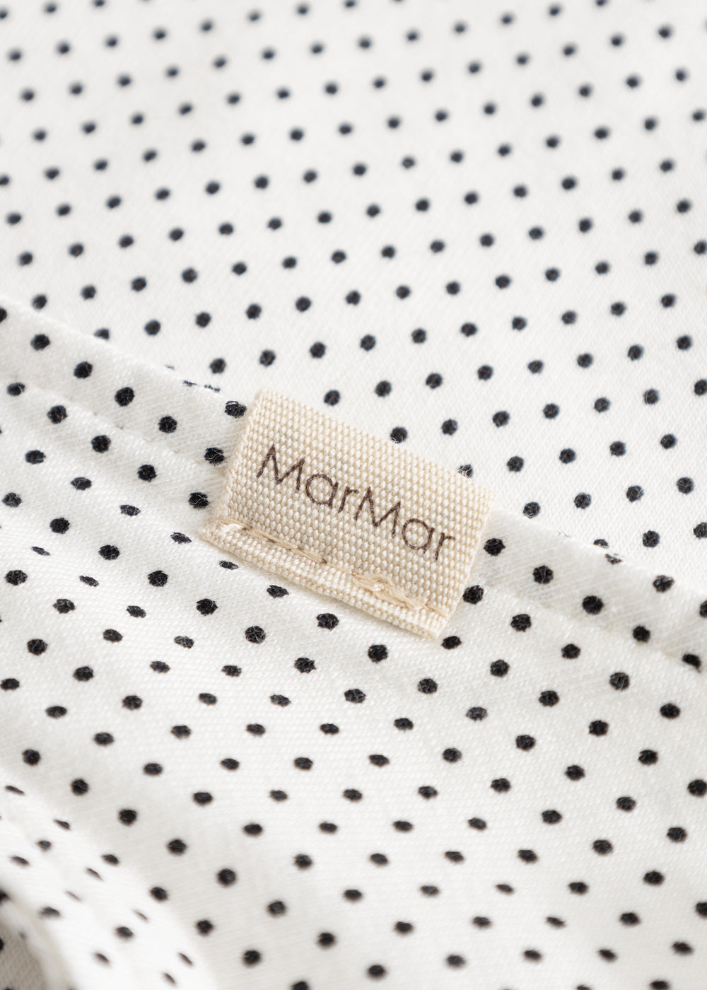 MarMar sweater in white with small black dots, triangular edge and beige label.