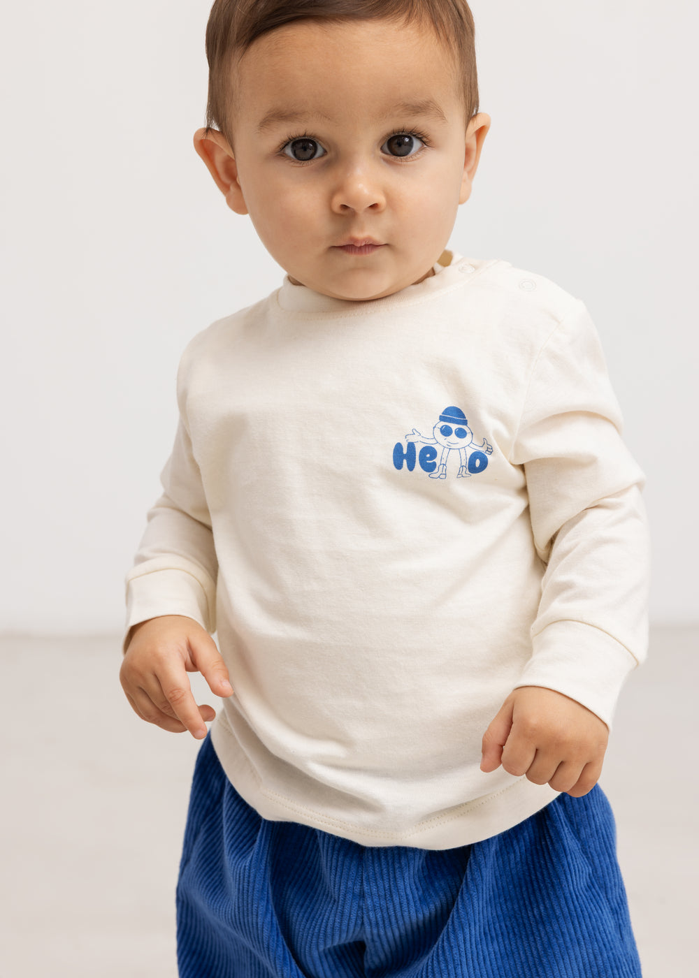 Long-sleeve blouse in cream with a blue "Hello" print on the chest.