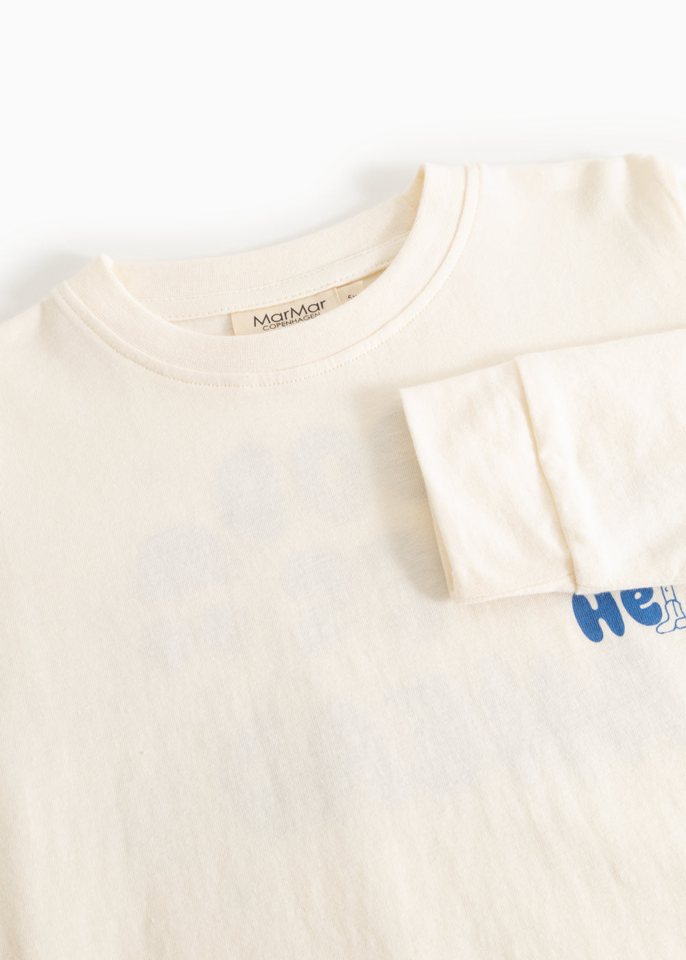 Cream long-sleeve blouse with round neck and blue "Hello" print on the right side.