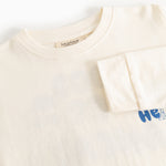 Cream long-sleeve blouse with round neck and blue "Hello" print on the right side.