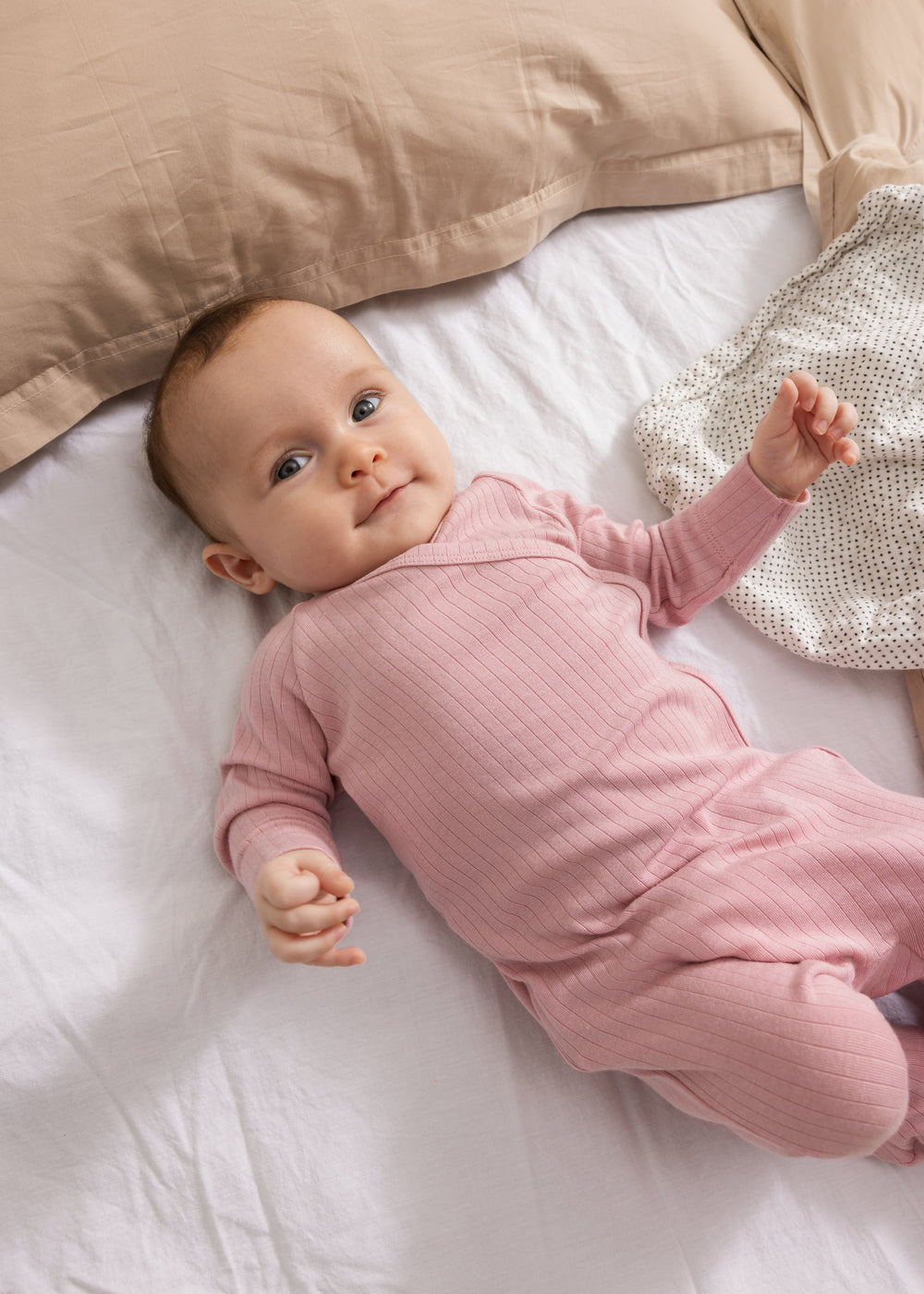 Pink baby jumpsuit with long sleeves and ribbed pattern.