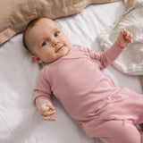 Pink baby jumpsuit with long sleeves and ribbed pattern.