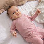 Linen with small black dots under baby, pink clothing visible