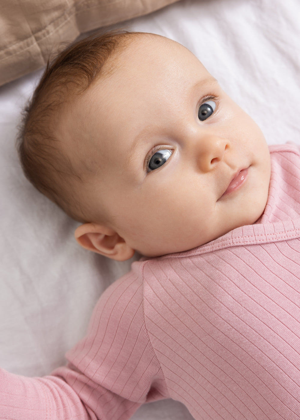 Pink baby jumpsuit with ribbed fabric and round neckline.