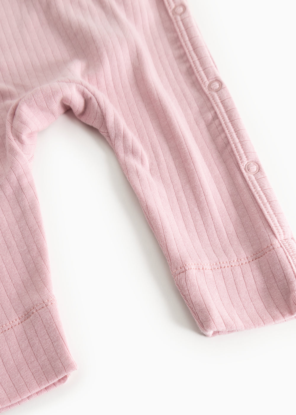 Pink jumpsuit in ribbed texture, long sleeves and leg opening with snap strap.