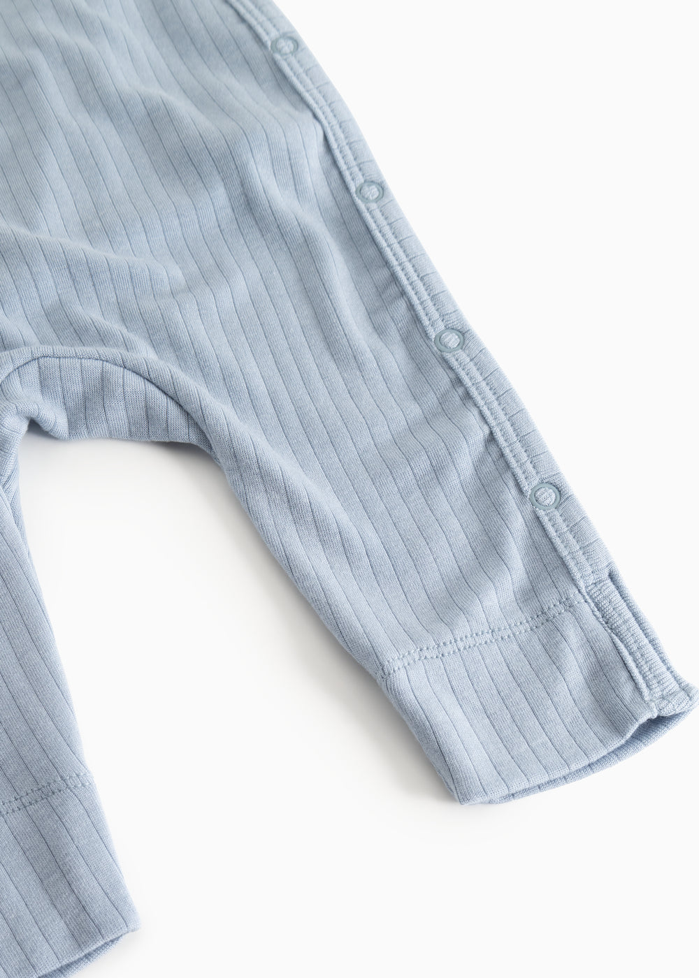 Light blue knitted jumpsuit with button closure at the shoulder, long sleeves and pants.