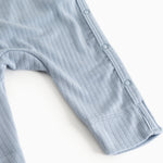 Light blue knitted jumpsuit with button closure at the shoulder, long sleeves and pants.
