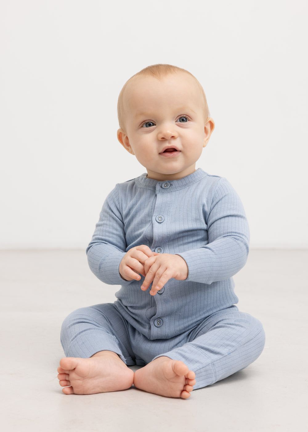 Light blue jumpsuit with button closure, carried by a full‑size baby.