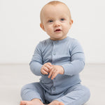 Light blue jumpsuit with button closure, carried by a full‑size baby.