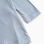 Blue evening dress with ribbed texture and round neckline, visible hem.