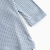 Blue evening dress with ribbed texture and round neckline, visible hem.