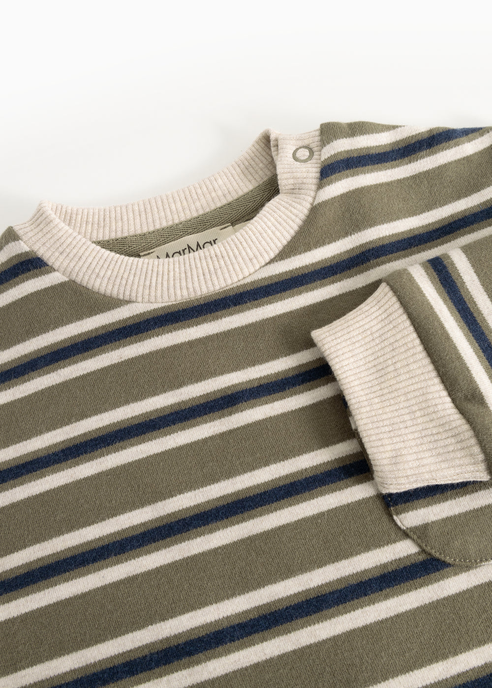 The strap is made of ribbed knit with a snap button at the neckline, as well as ripped cuffs.