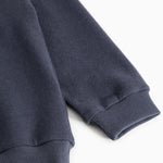 Navy blue sleeve with ribbed cuff at the wrist.