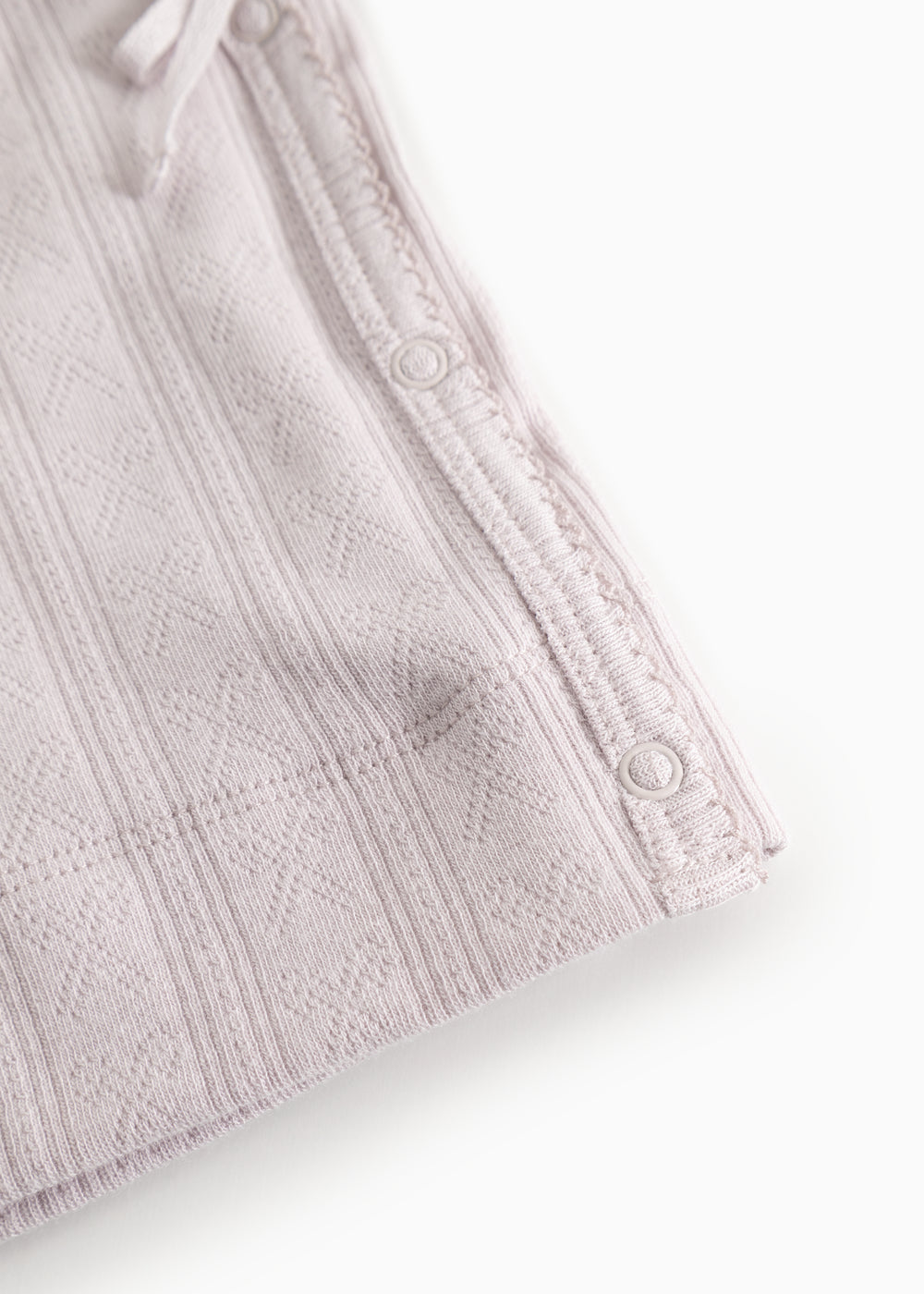 The lace detail with buttons along the edge and textured fabric.