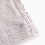 The lace detail with buttons along the edge and textured fabric.