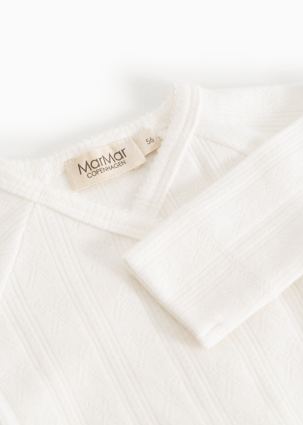 Baby romper in cream white with MaMar logo on the collar.