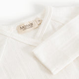 Baby romper in cream white with MaMar logo on the collar.