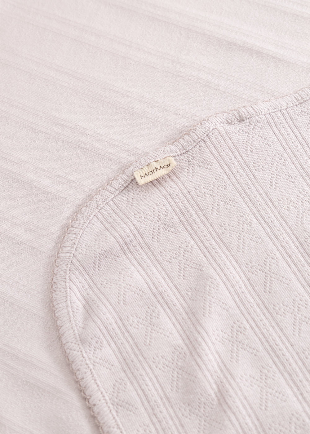Light pink corner rug with woven pattern, border tape, and sewn-in label.