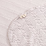 Light pink corner rug with woven pattern, border tape, and sewn-in label.