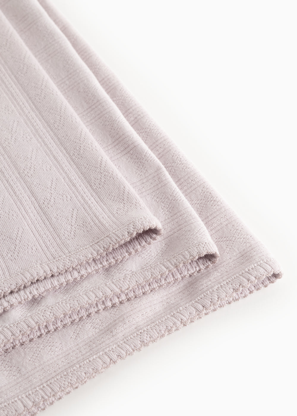 Light lilac rug in woven pattern with fringe edge and stitching along the edge.