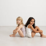 Two girls in a white underwear set with top and panties, both with thin straps.