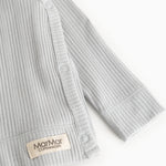Light gray ribbed blouse with long sleeves and a snap button at the opening.